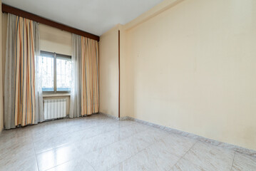 Empty room with windows with curtains and net curtains, niche with white aluminum radiator and large stoneware floors