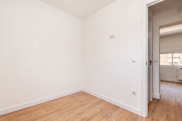 Empty room in a renovated apartment with plain white painted walls, white woodwork and oak colored parquet floors