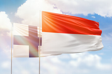 Sunny blue sky and flags of indonesia and finland