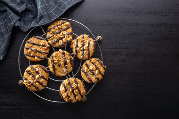 Chip cookies with peanuts and chocolate strips on black table.