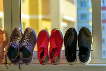 Multi-colored sneakers are dried on the windowsill after playing sports