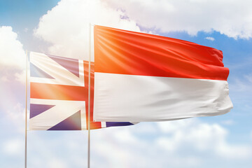 Sunny blue sky and flags of indonesia and great britain