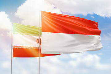 Sunny blue sky and flags of indonesia and iran