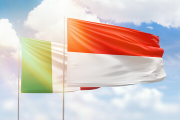 Sunny blue sky and flags of indonesia and italy