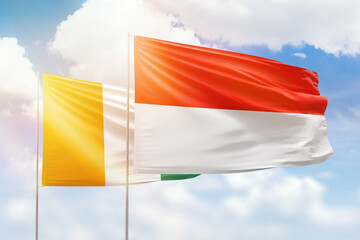 Sunny blue sky and flags of indonesia and ivory coast