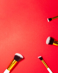 Top view of cosmetics brushes set for makeup at the bottom on red background. Cosmetics and beauty concept. Makeup concept with copy space flat lay