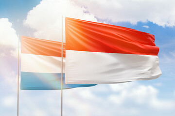 Sunny blue sky and flags of indonesia and luxembourg
