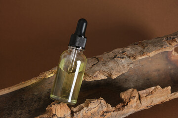 glass dropper bottle with serum or oil on the bark