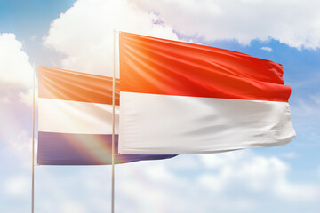 Sunny blue sky and flags of indonesia and netherlands