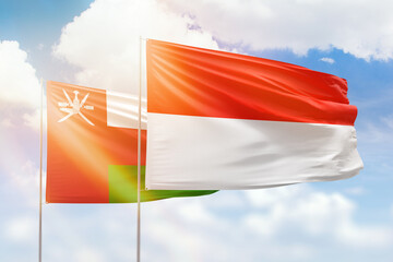 Sunny blue sky and flags of indonesia and oman