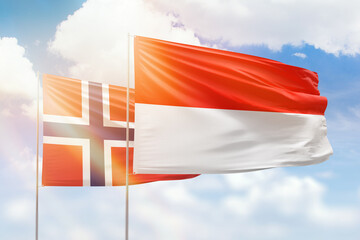 Sunny blue sky and flags of indonesia and norway