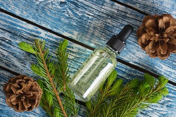 glass dropper bottle with cosmetic serum or oil and sprig of spruce with fresh shoots, young shoots...