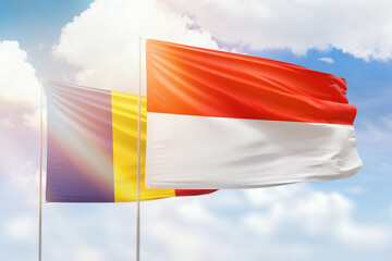 Sunny blue sky and flags of indonesia and romania