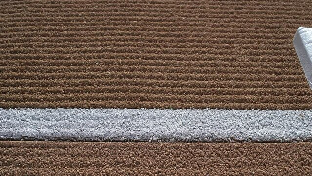 A high angle slider shot along a freshly groomed first base path and white baseline stop over first base  