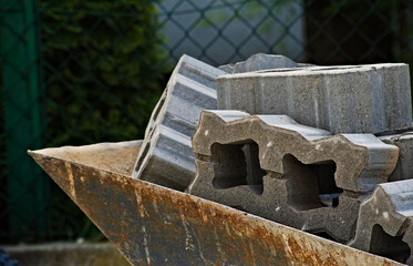 Kostki brukowe , ażurowe ( betonowe bloczki z dziurkami  ) , przeznaczone do brukowania podjazdu , złożone w taczce .