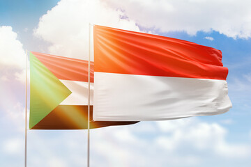 Sunny blue sky and flags of indonesia and sudan