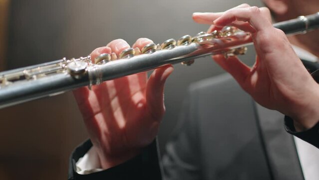 flute in hands of talented musician, flutists is playing classic music in opera house or philharmonic hall