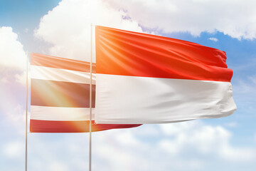 Sunny blue sky and flags of indonesia and thailand