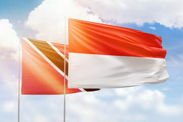 Sunny blue sky and flags of indonesia and trinidad and tobago