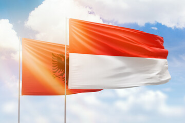 Sunny blue sky and flags of indonesia and albania