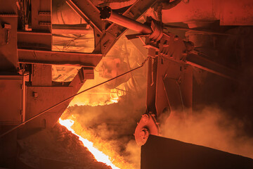 Hot red melting slag is pouring from blast furnace tap hole.