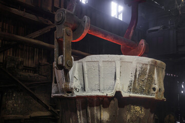 The crane carries the container with slag.