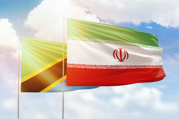 Sunny blue sky and flags of iran and tanzania