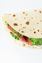 Italian street food flat lay with piadina isolated on a white background.  Piadina romagnola - Italian flatbread with prosciutto, salad and cream cheese