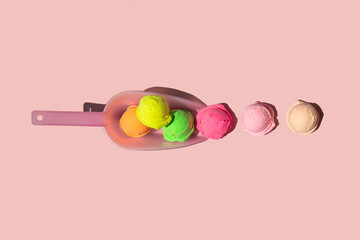 Pastel light ice cream balls in scoop on light pastel pink background. Creative food concept. Minimalistic sweets composition. Sunny summer day idea.