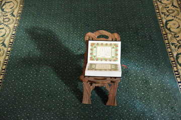 The Holy Qur’an on a wooden stand in the mosque, prayer and supplication in the mosque, worship and getting closer to God