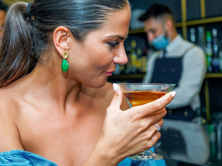 Closeup of liquor glass held by young Caucasian girl looking to the side. Selective focus.