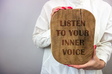 Businesswoman holding wooden board with inspirational advice - listen to your inner voice