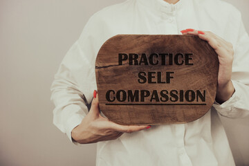 Practice self compassion inspirational text on wooden board