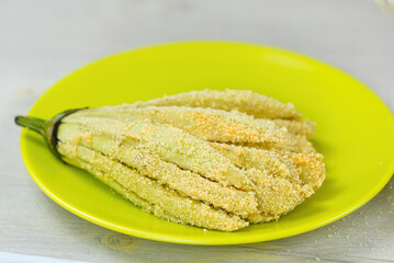 Coated sliced eggplant with breadcrumbs on the green plate. close up