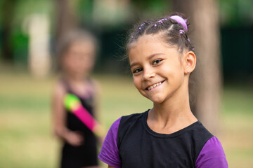 Portrait of smiling girl trainee on rhythmic gymnastics training in summer in sports camp outdoors