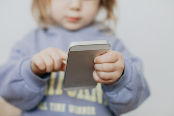 Little girl in violet hoodie using a phone on white background