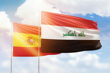 Sunny blue sky and flags of iraq and spain