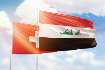 Sunny blue sky and flags of iraq and switzerland