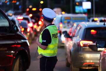 Policjantka kieruje ruchem drogowym wieczorem podczas szczytu w korkach ulicznych.  © FotoDax