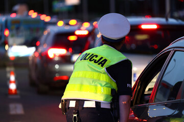 Policjantka kieruje ruchem drogowym wieczorem podczas szczytu w korkach ulicznych.  - obrazy, fototapety, plakaty