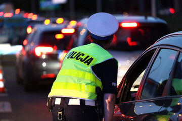 Policjantka kieruje ruchem drogowym wieczorem podczas szczytu w korkach ulicznych.  - obrazy, fototapety, plakaty