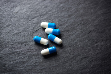 Sports Supplements (creatine capsules) on dark stone background. Close up. Copy space.