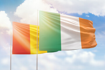 Sunny blue sky and flags of ireland and guinea