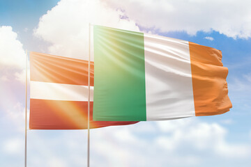 Sunny blue sky and flags of ireland and latvia