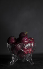 plums inside a glass container with black background