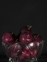 plums inside a glass container with black background