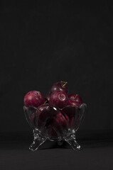 plums inside a glass container with black background