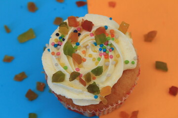 Sweet cake with tutti frutti sprinkles on top on the color background.