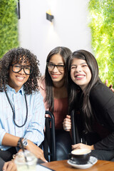 three female friends sharing and smiling at a coffeeshop