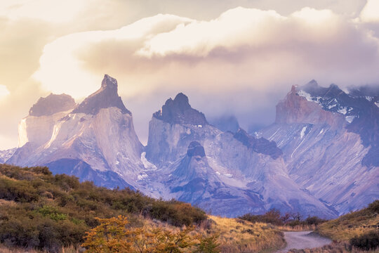 camino hacia cuernos torres del Paine, octava maravilla del mundo, Magallanes, entre montes y cerros en atardecer con nubes moradas 